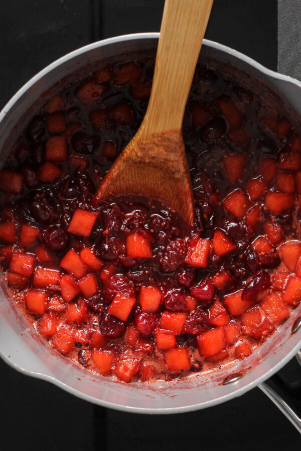 A saucepan with cooked apple cranberry sauce inside.