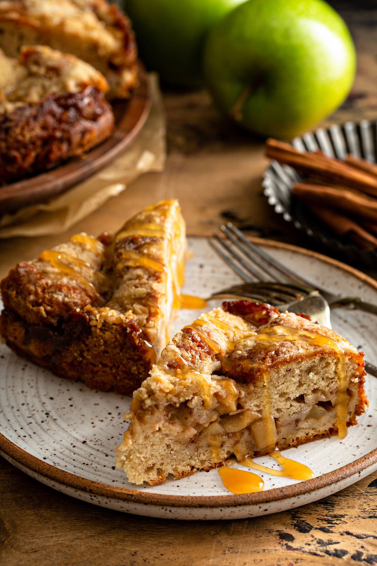 Two slices of Apple Streusel Cake on a white plate with caramel drizzled on top.