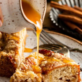 A slice of Apple Streusel Cake on a white plate with caramel being drizzled on top.