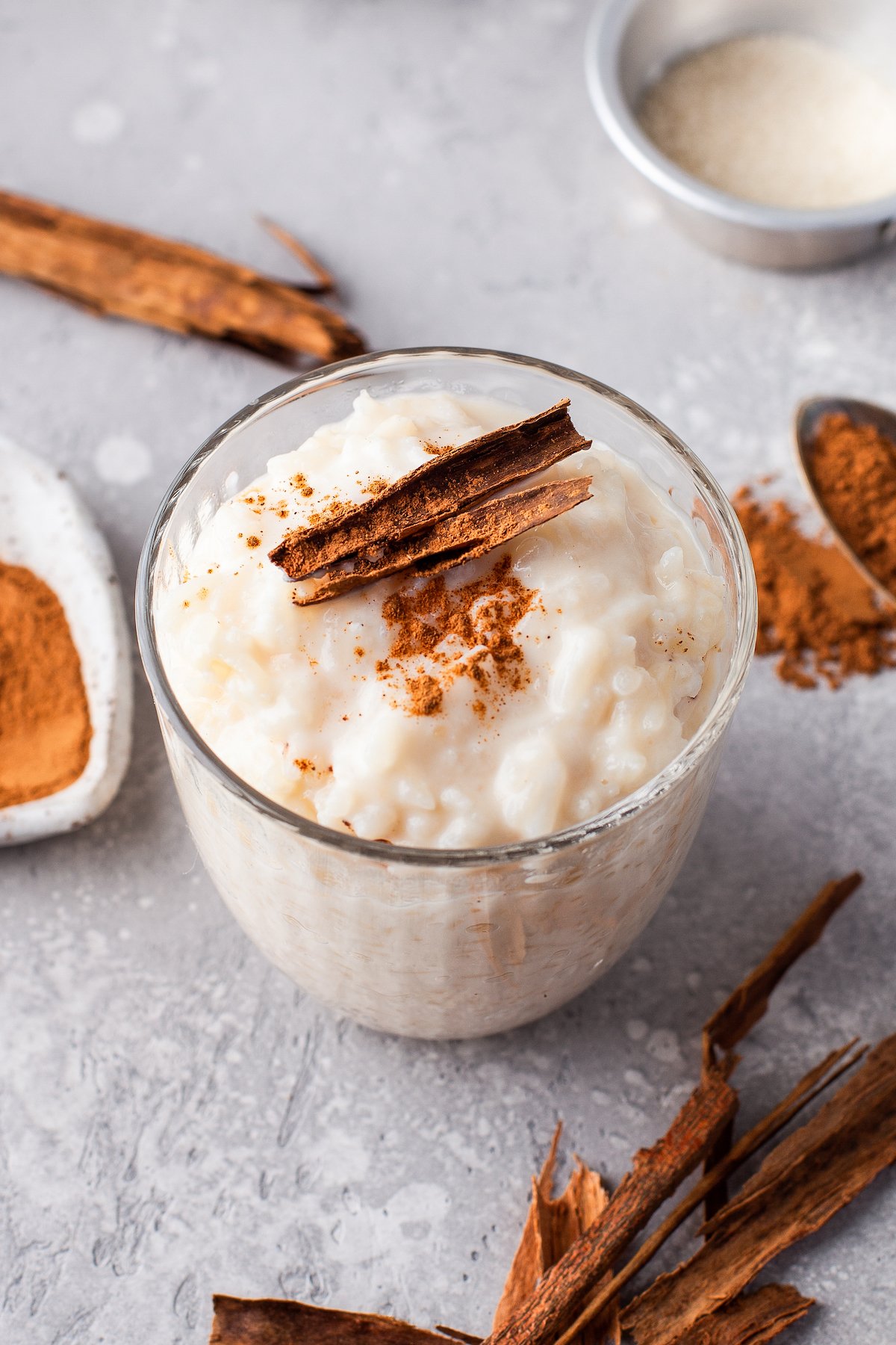 A serving of chilled arroz con leche (Spanish rice pudding) with a toasted cinnamon stick garnish on top.