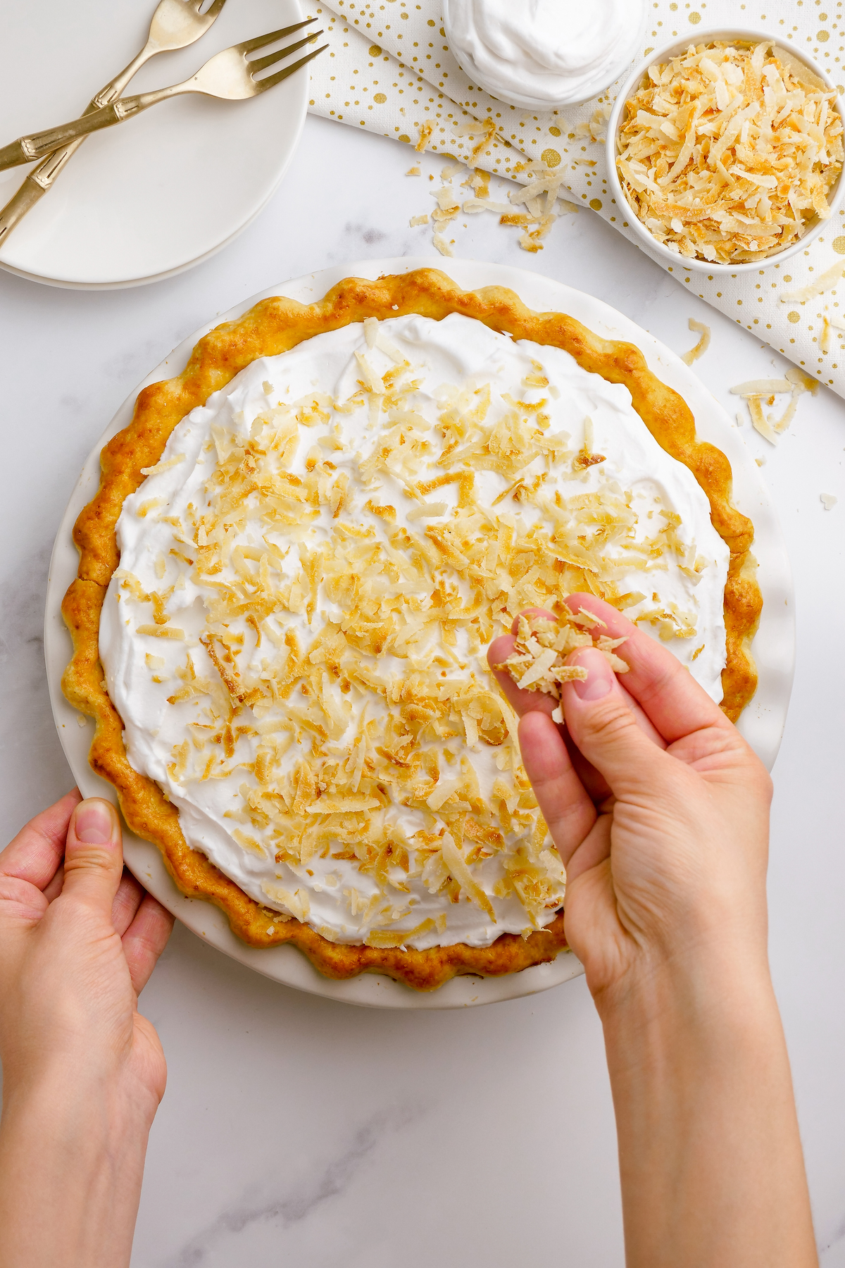 A coconut cream pie being decorated with sweetened toasted coconut.
