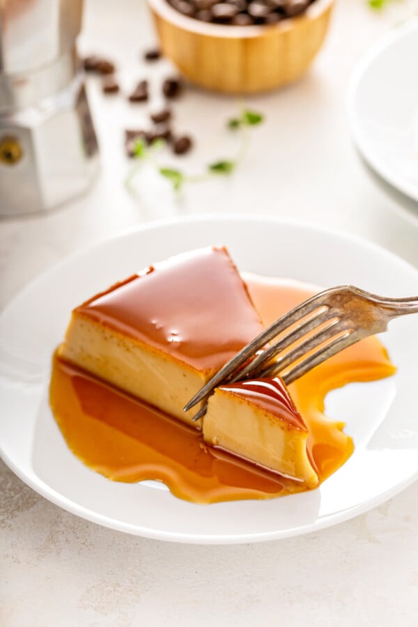 A slice of flan with a fork cutting a bite.