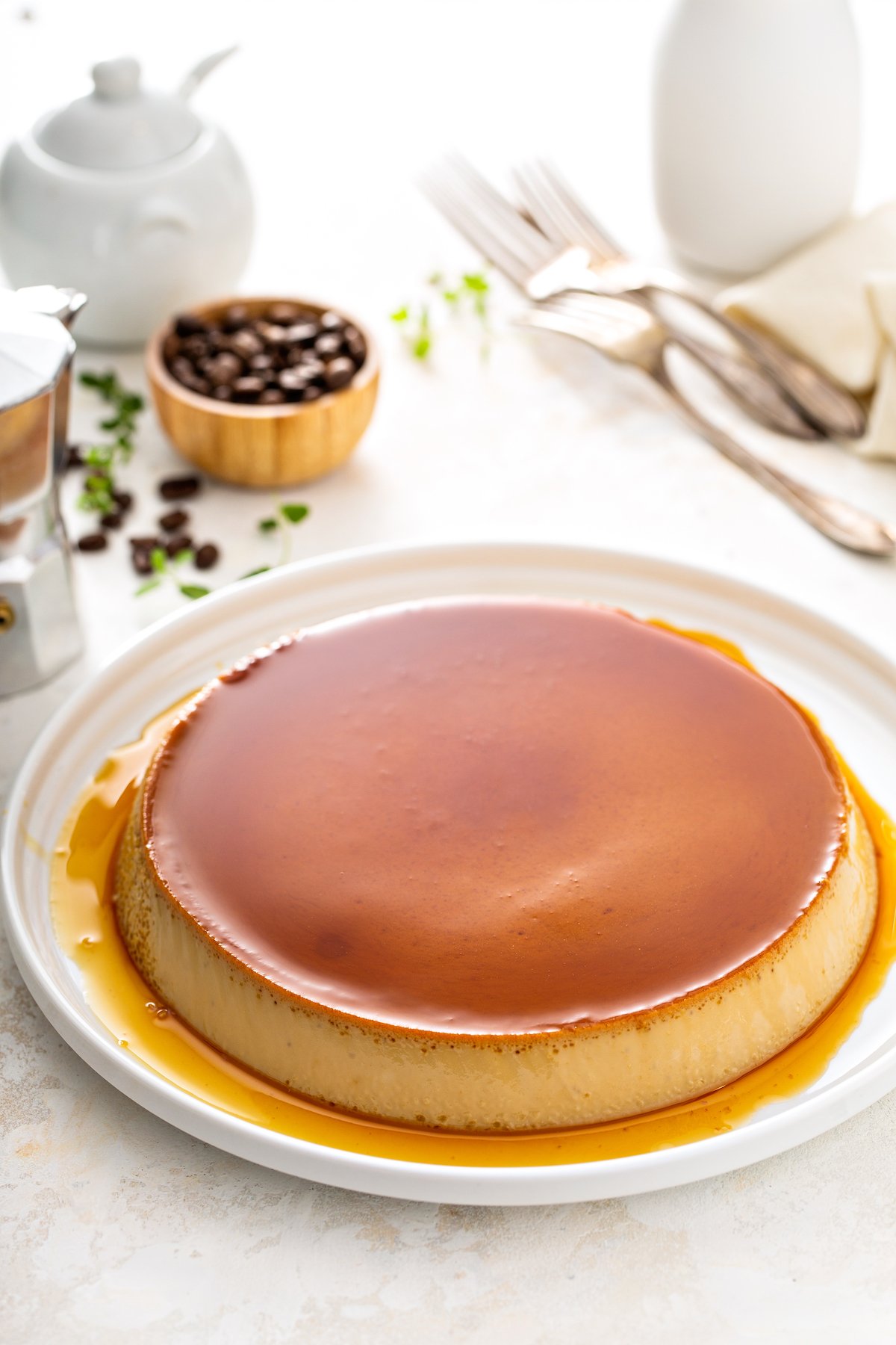 Coffee flan on a white plate with flan syrup poured on top.