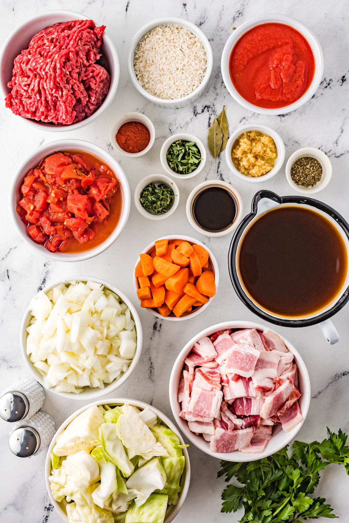 Clockwise from top: White rice, tomato sauce, garlic, herbs, bay leaves, Worcestershire sauce, carrots, beef broth, bacon, fresh parsley, chopped cabbage, salt and pepper, chopped onions, caned tomatoes, spices, ground beef.
