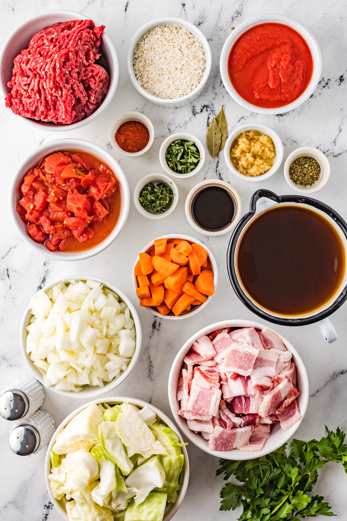 Clockwise from top: White rice, tomato sauce, garlic, herbs, bay leaves, Worcestershire sauce, carrots, beef broth, bacon, fresh parsley, chopped cabbage, salt and pepper, chopped onions, caned tomatoes, spices, ground beef.