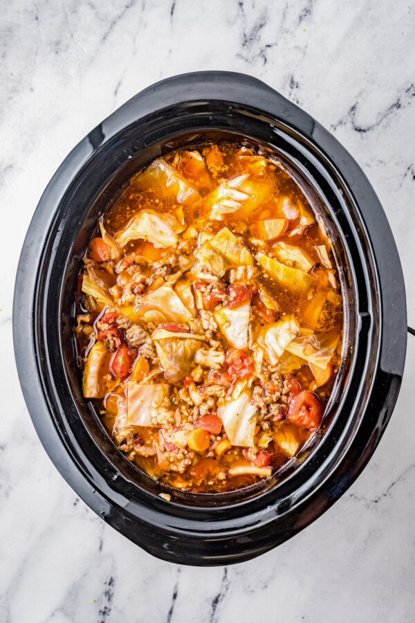 Overhead shot of an oval Crockpot insert, filled with cooked cabbage roll soup.