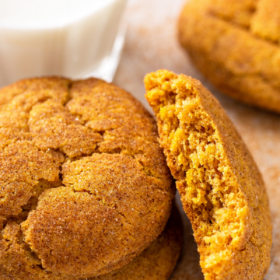 Pumpkin Snickerdoodles stacked on top of each other with a glass of milk on a platter.
