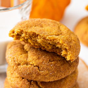 Four pumpkin snickerdoodle cookies stacked on top of each other with the top one with a bite taken out of it.