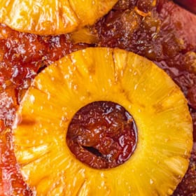 Up close image of the top of a ham with pineapple slices on top.