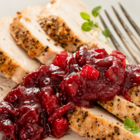Up close image of sliced turkey with homemade apple cranberry sauce on top.