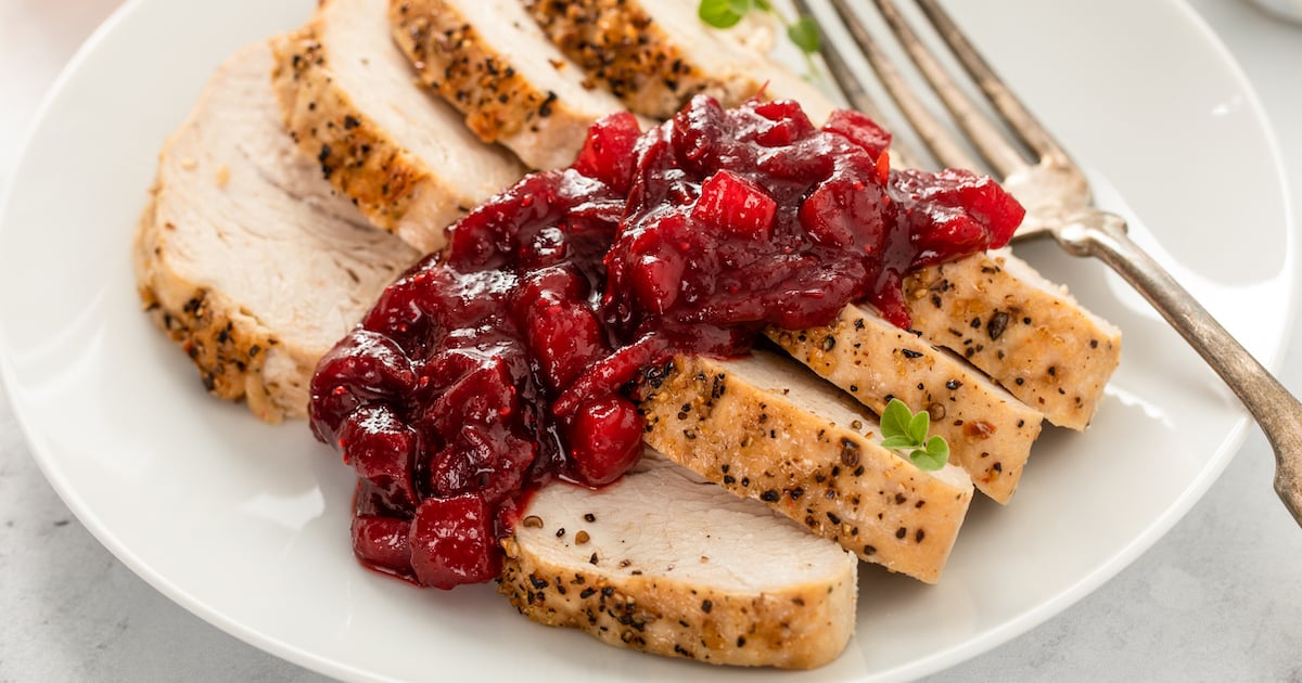 Up close image of sliced turkey with homemade apple cranberry sauce on top.