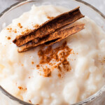 Up close image of arrz Con Leche in a glass jar with cinnamon on top.