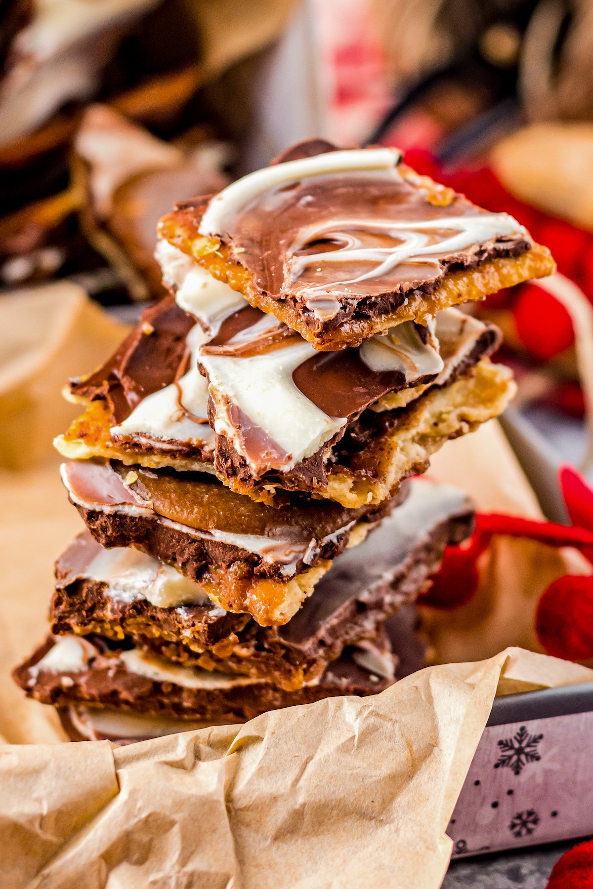 Pieces of chocolate saltine toffee candy stacked on top of each other in a paper-lined tray.