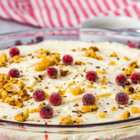 Cranberry jello salad in a glass bowl with cream cheese frosting on top.