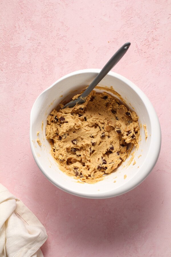 A white mixing bowl filled with peanut butter chocolate chip cookie dough.