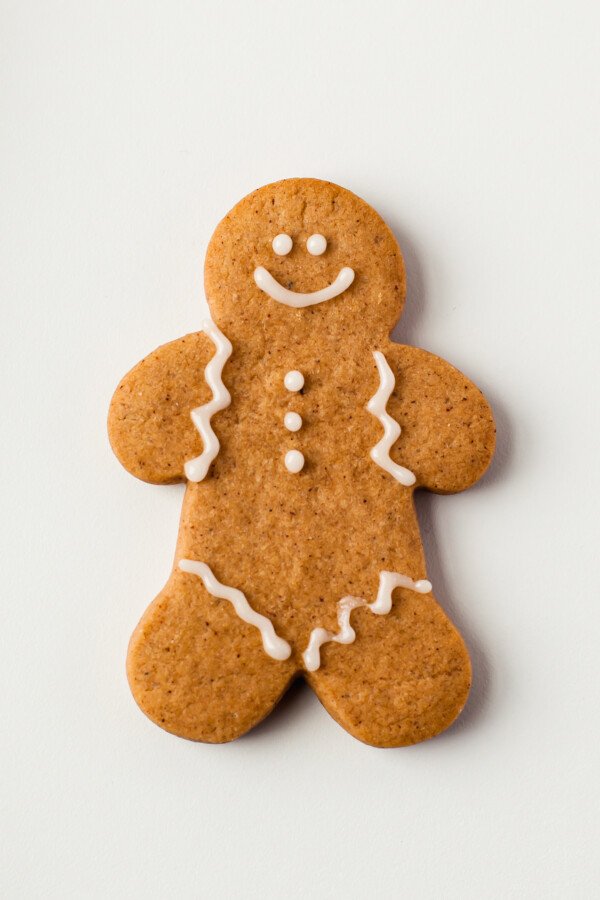 A gingerbread man with piped eyes, mouth, zigzag sleeves and pants, and buttons.
