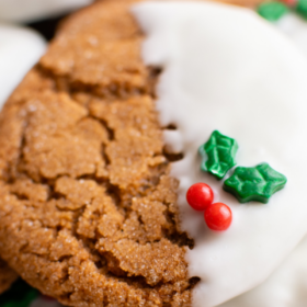 Up close image of holly sprinkles on a gingersnap cookie dipped in white chocolate.