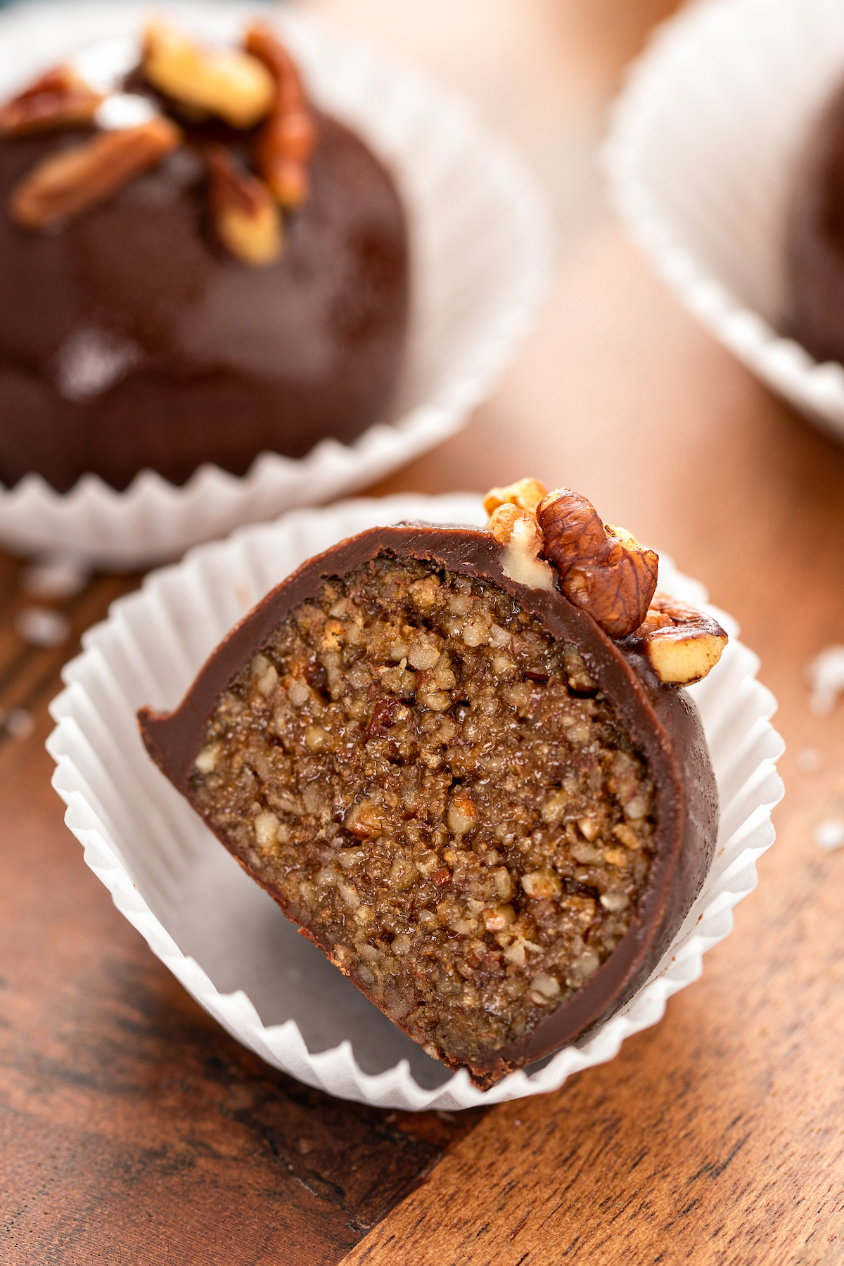 Up close image of a pecan pie truffle sliced in half to show the bourbon pecan pie filling.