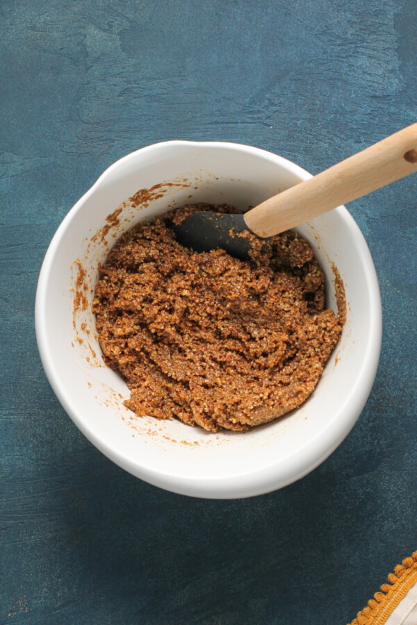 Pecan pie filling in a white bowl with a spatula.