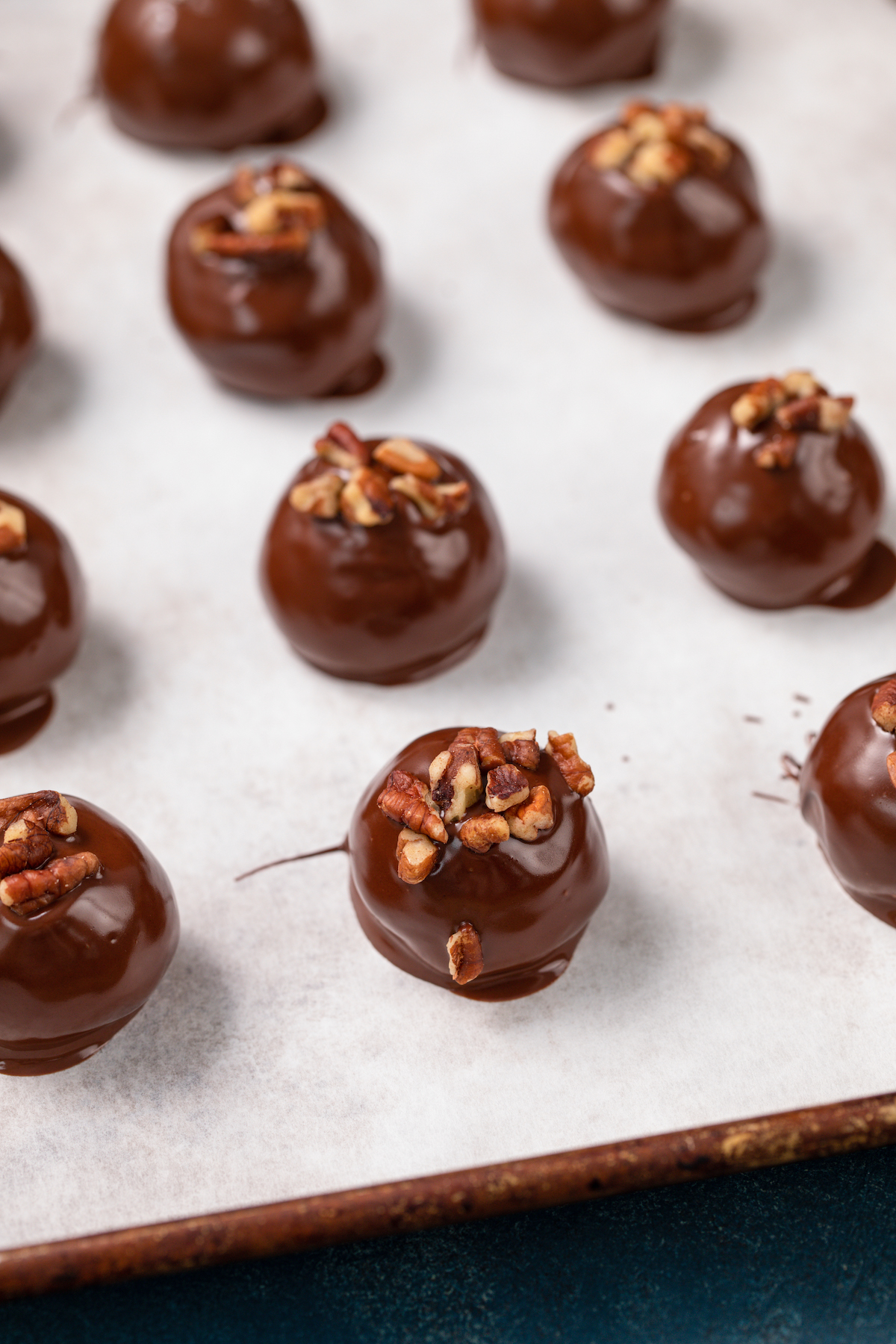 Pecan pie truffles lined up on a cookie sheet with parchment paper.
