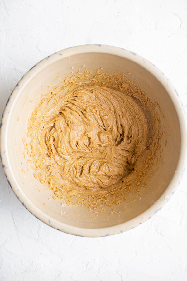 Cookie dough batter in a brown bowl on a white background.