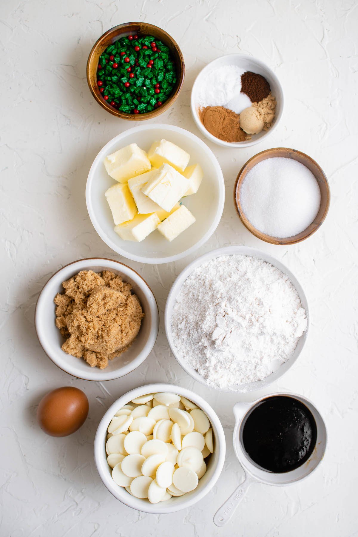 Ingredients in white bowls for gingersnap cookies on a white background.