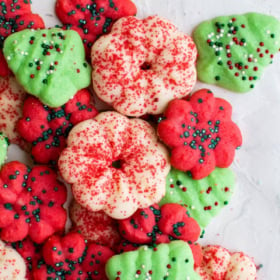 Spritz cookies arranged on a piece of parchment paper with sprinkles.