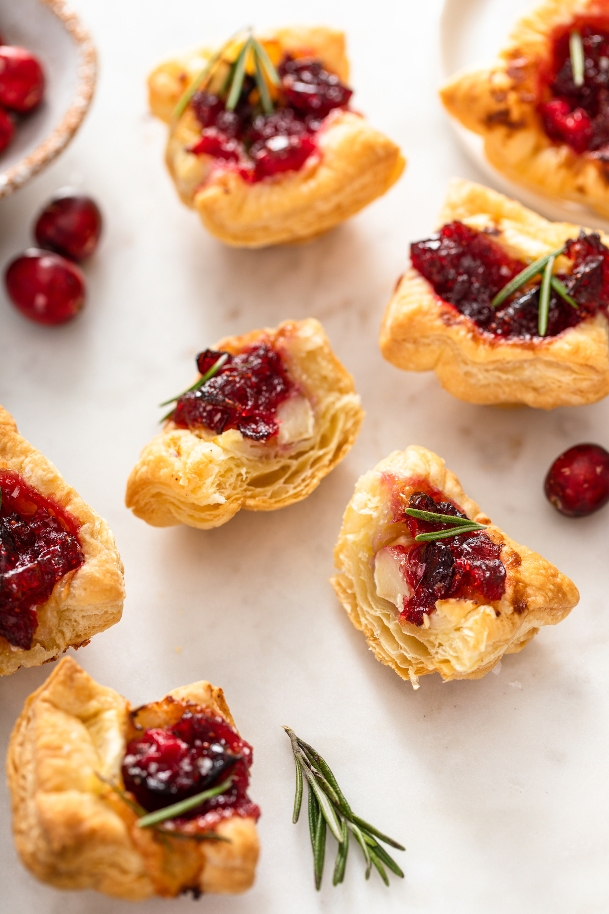 Cranberry Brie Bites wrapped in puff pastry on a marble background.