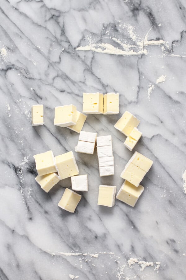 Brie cut into squares on a marble background.