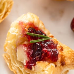 Cranberry brie bite sliced in half on a marble background.