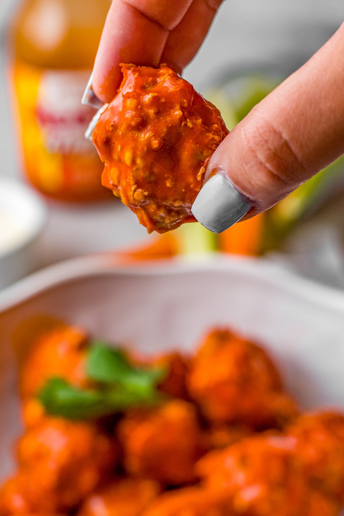 A hand holding one buffalo chicken meatball, to show texture.