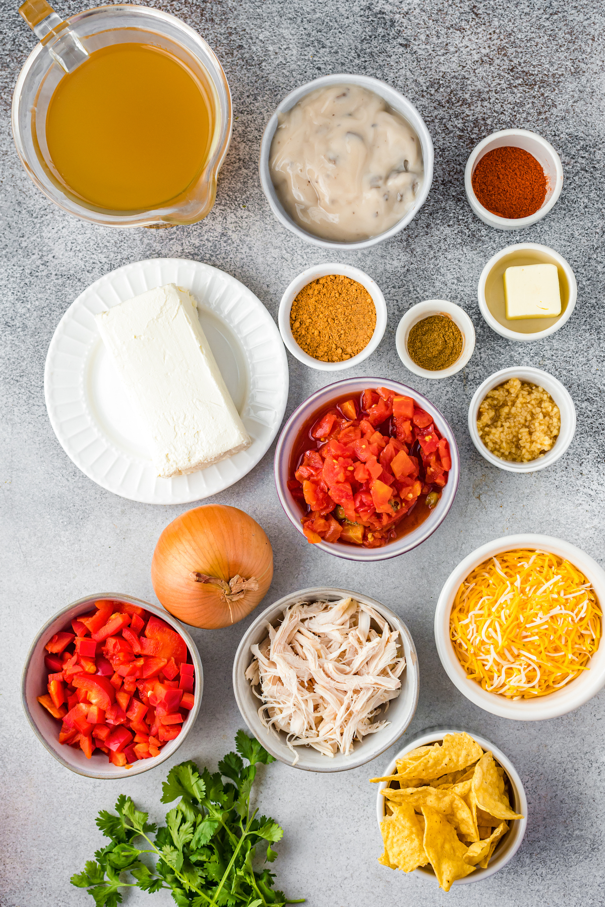 Clockwise from top left: Chicken broth, cream of mushroom soup, chili powder, butter, cumin, garlic, rotel tomatoes, shredded cheese, tortilla chips, shredded chicken, cilantro, onion, cream cheese.