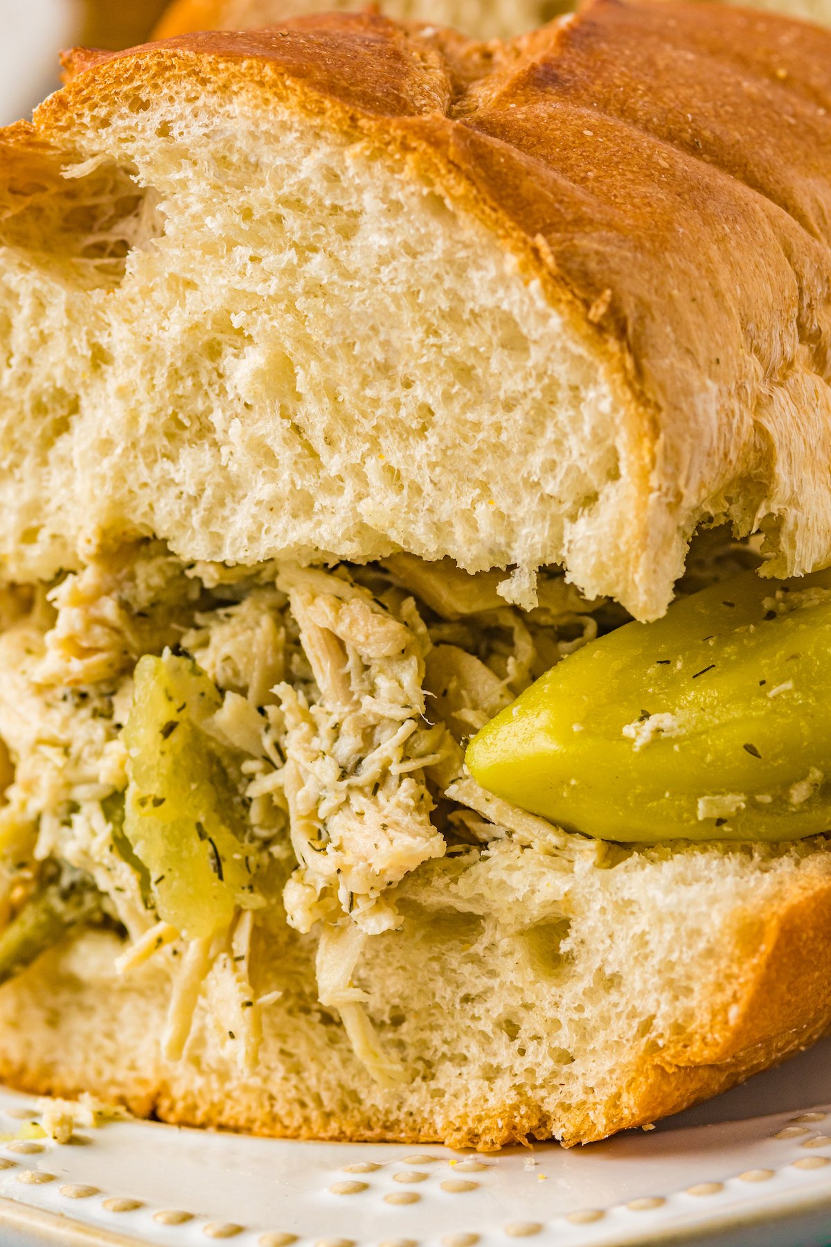 Close-up shot of a Mississippi chicken sandwich on a baguette, showing the texture of the chicken and bread.