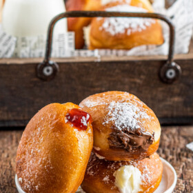 Three homemade filled donuts on a plate. Each with a different filling.