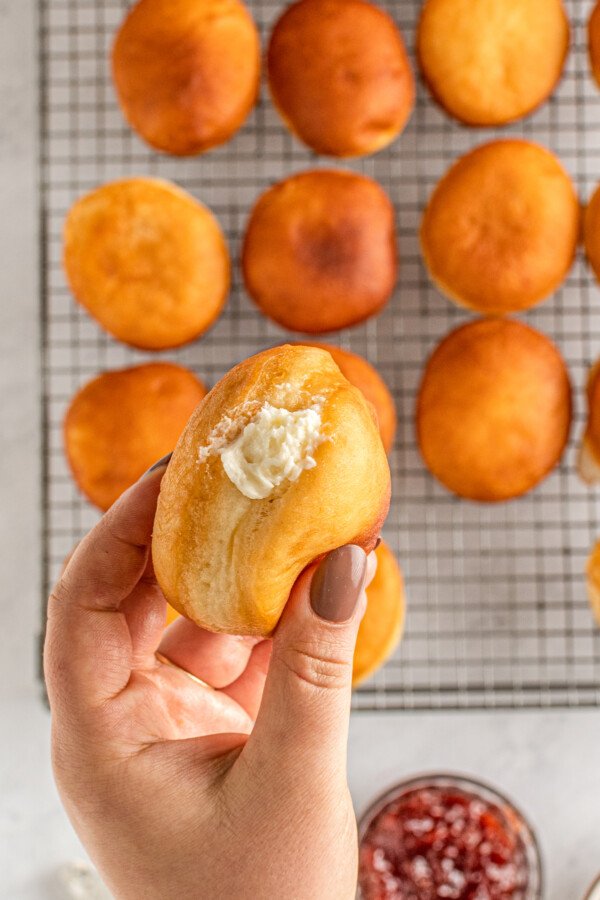 A woman's hand holding a cream-cheese filled donut.