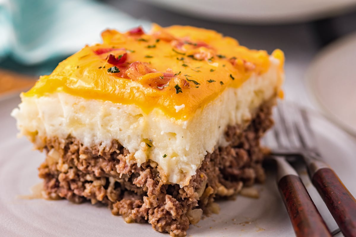 Close-up of a square of meatloaf casserole, showing the layers of meat, potato, and cheese.