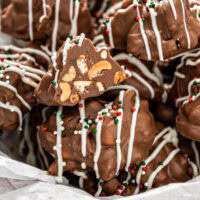 Crockpot candy inside a tin with tissue paper with one cluster cut in half.