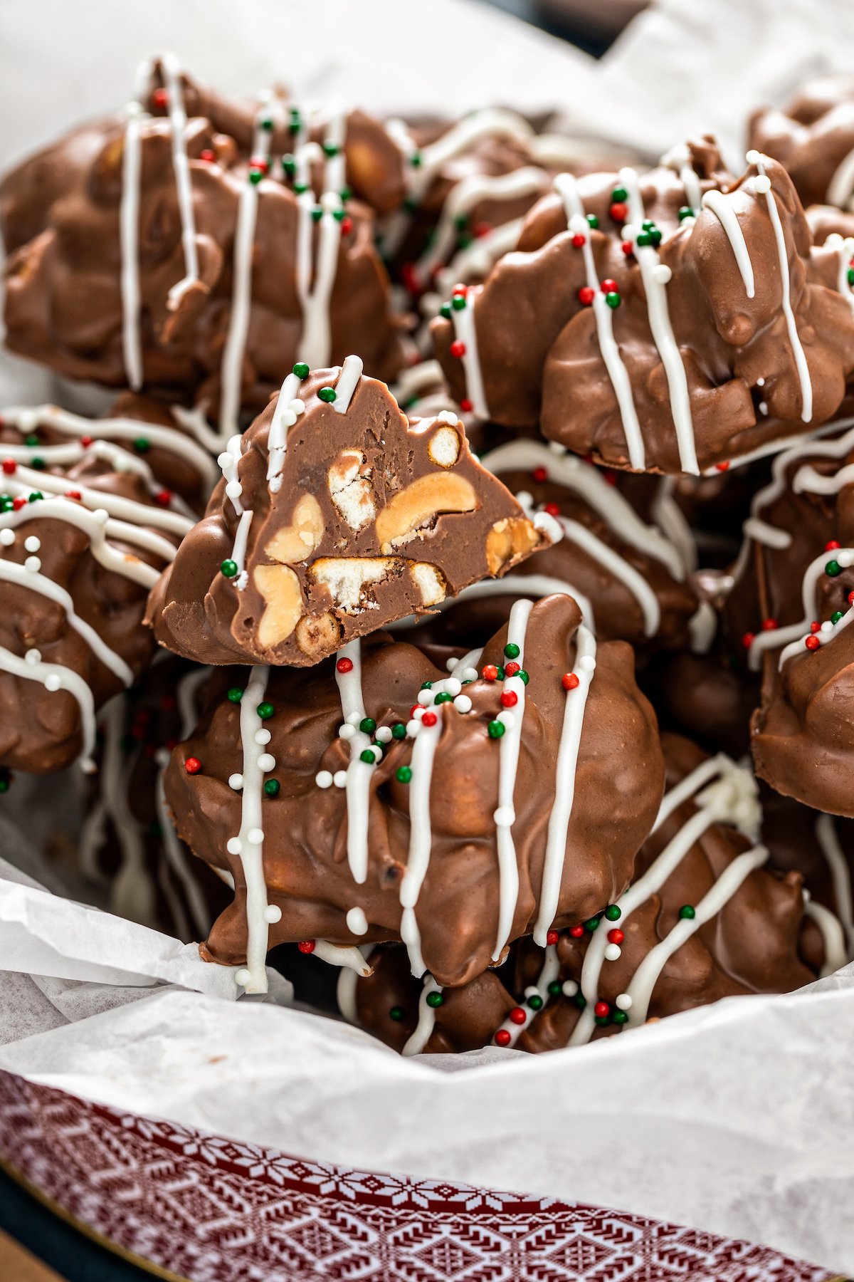 Crockpot candy inside a tin with tissue paper with one cluster cut in half.