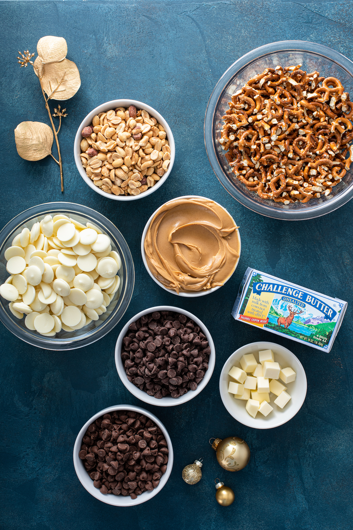 Overhead image of ingredients for crockpot candy in white bowls on a blue background.