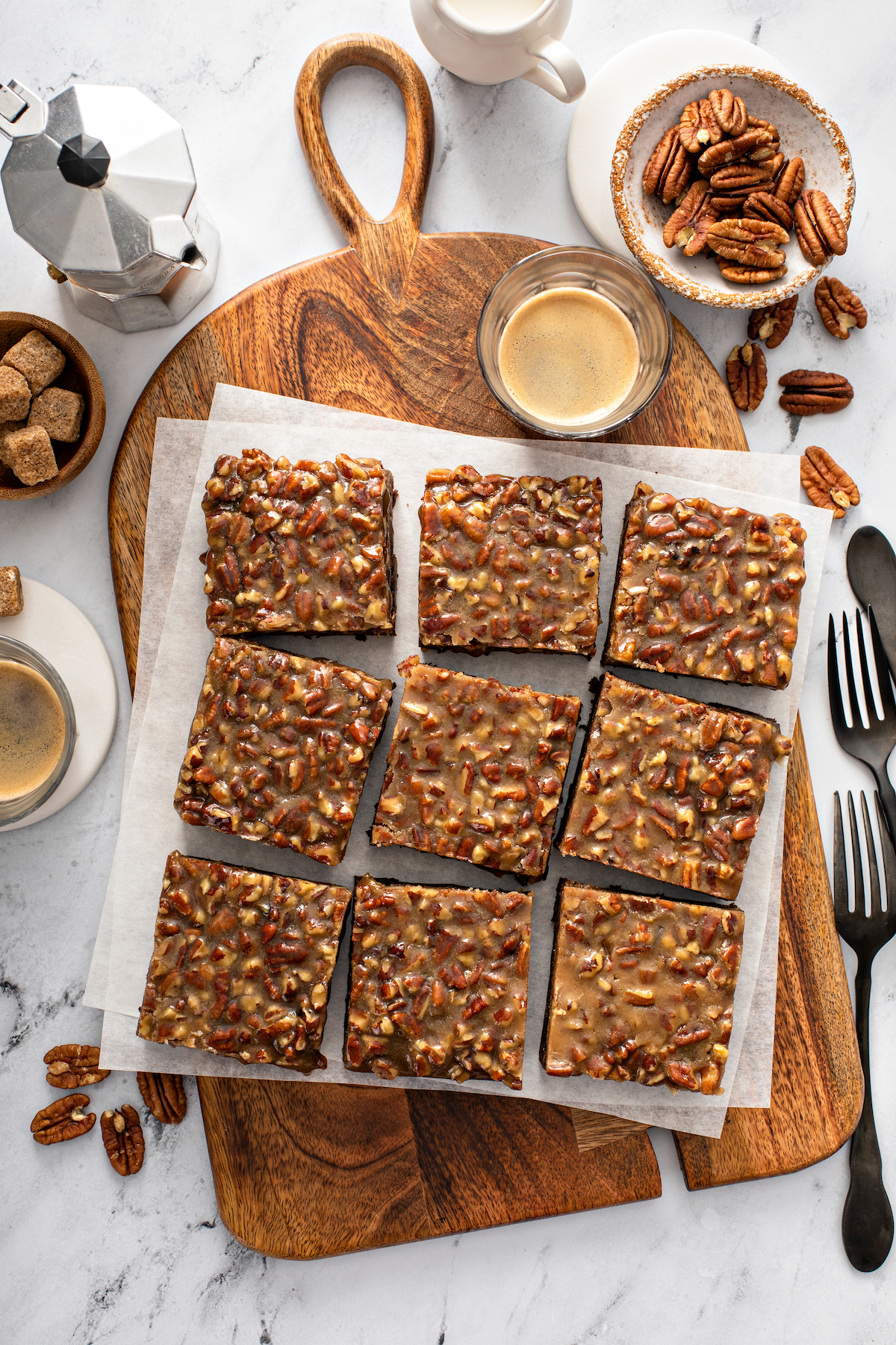 Pecan pie brownies sliced into squares on parchment paper on a cutting board.