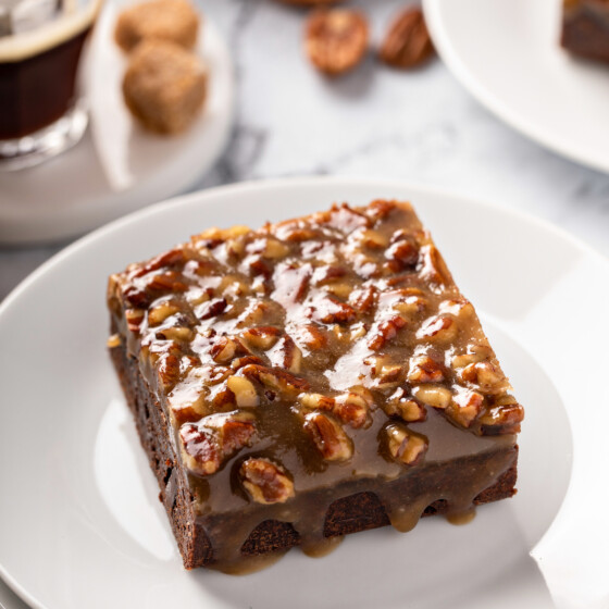 Chocolate brownies with pecan pie topping set on top of a white plate.