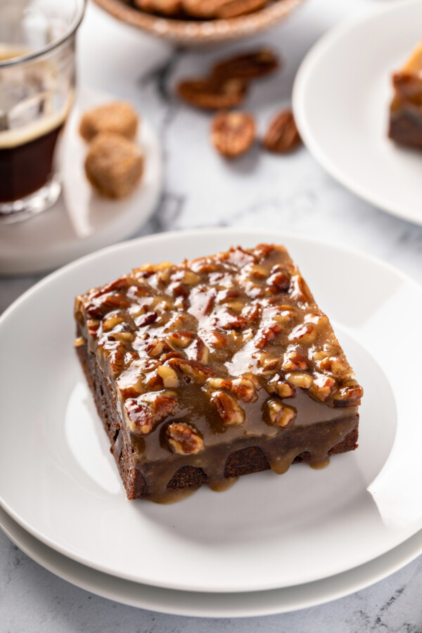 Chocolate brownies with pecan pie topping set on top of a white plate.
