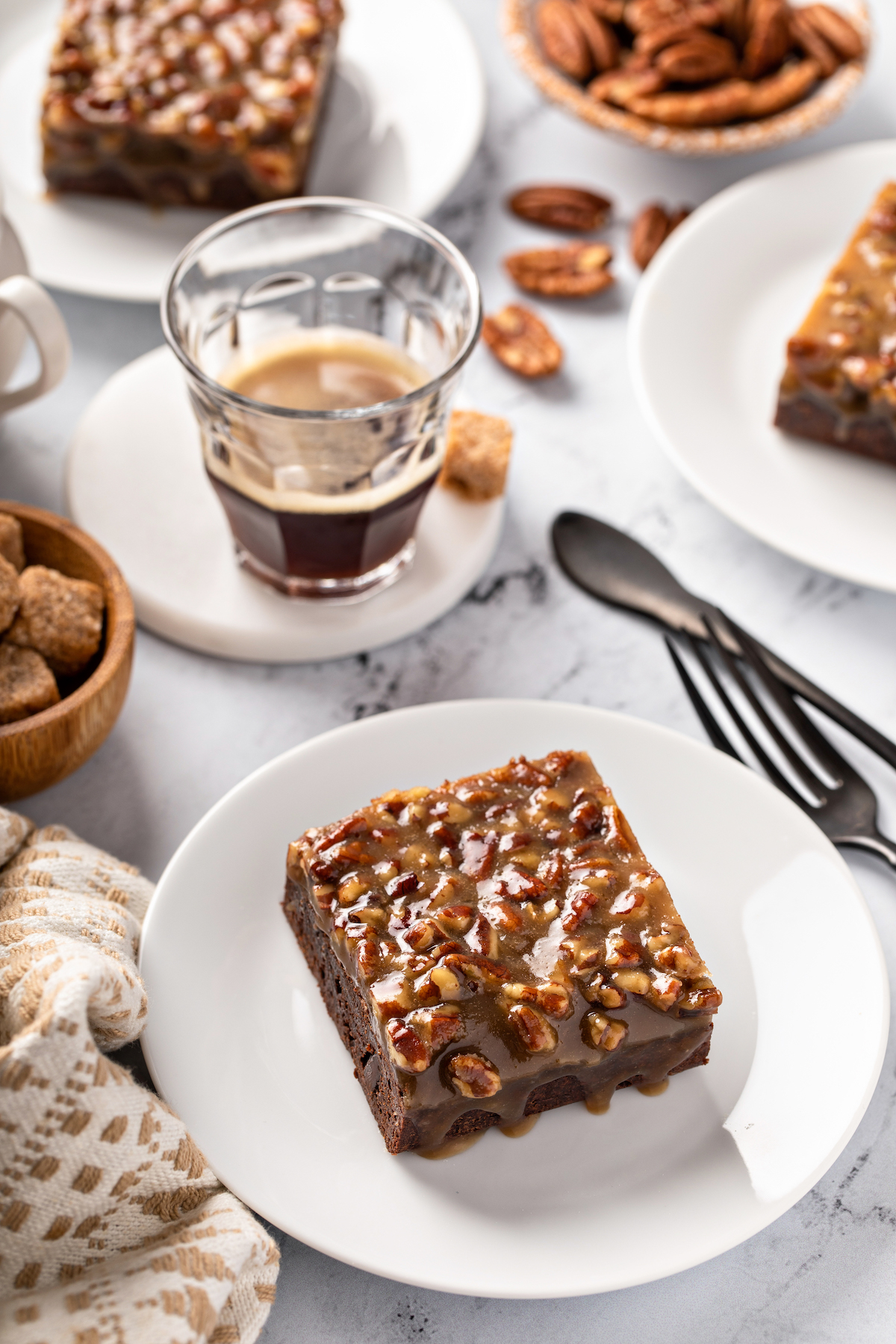 Pecan pie brownies on a white plate with a cup of coffee.