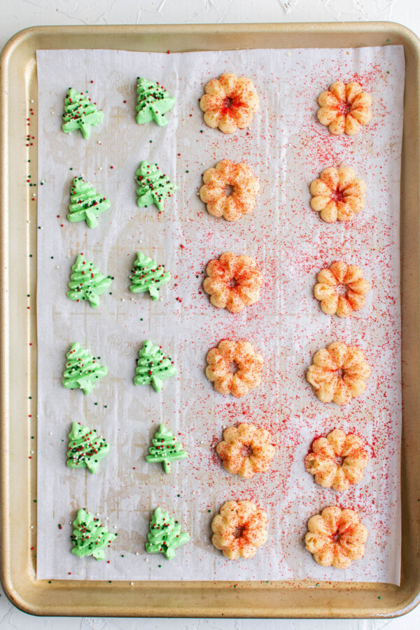 Christmas and wreath spritz cookies with red sprinkles on a. cookie sheet.