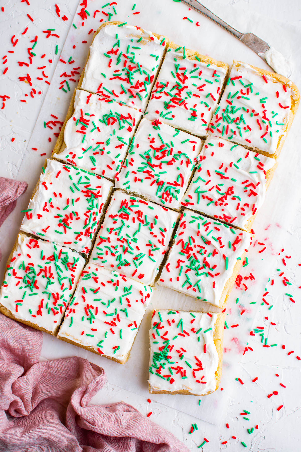 Overhead view of sugar cookie bars with white icing and red and green sprinkles.