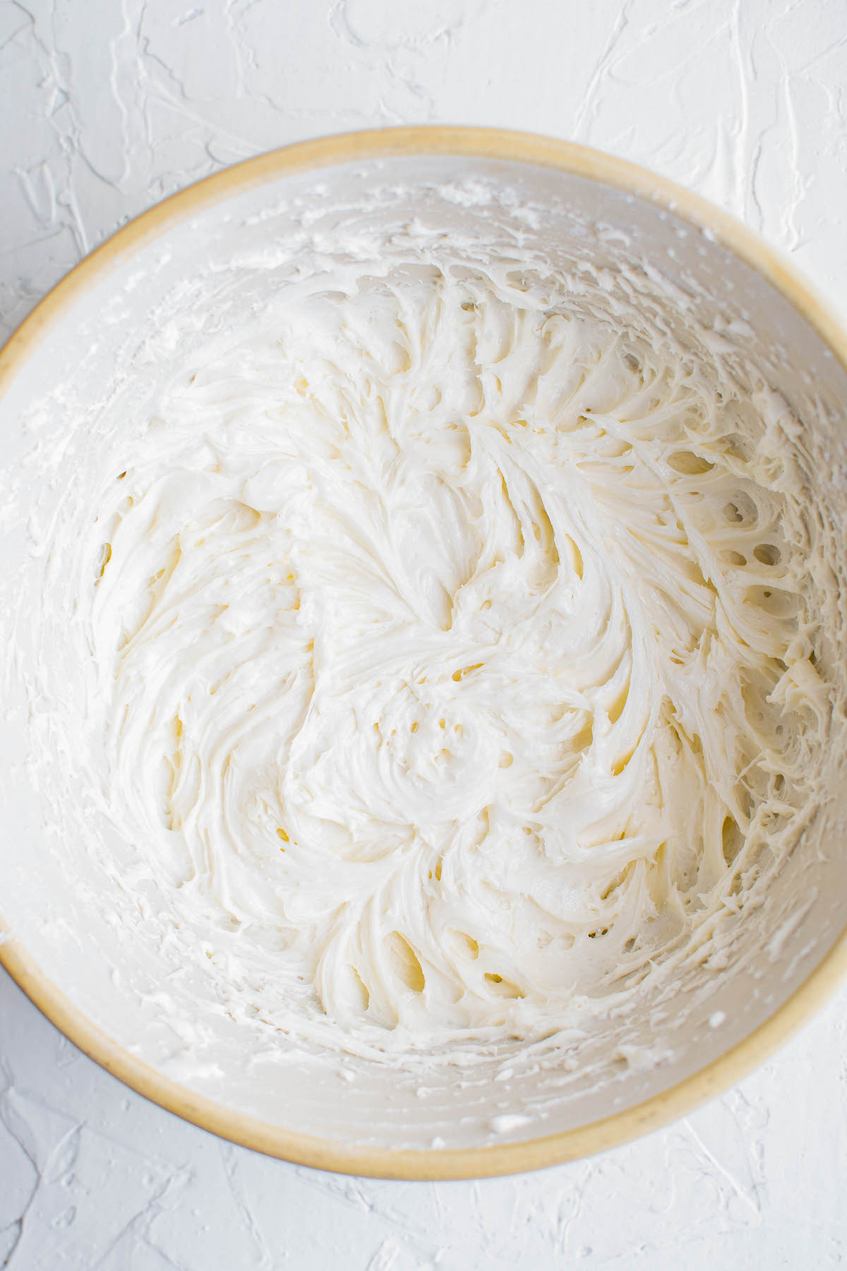 White frosting beat into a mixing bowl.