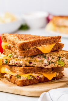 Tuna melt sandwich halves, stacked on top of each other, to show the filling and cheese from the side.