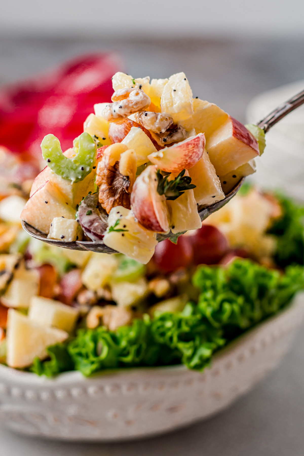 A serving of chopped salad, with a spoon lifting out a portion from the dish toward the camera.