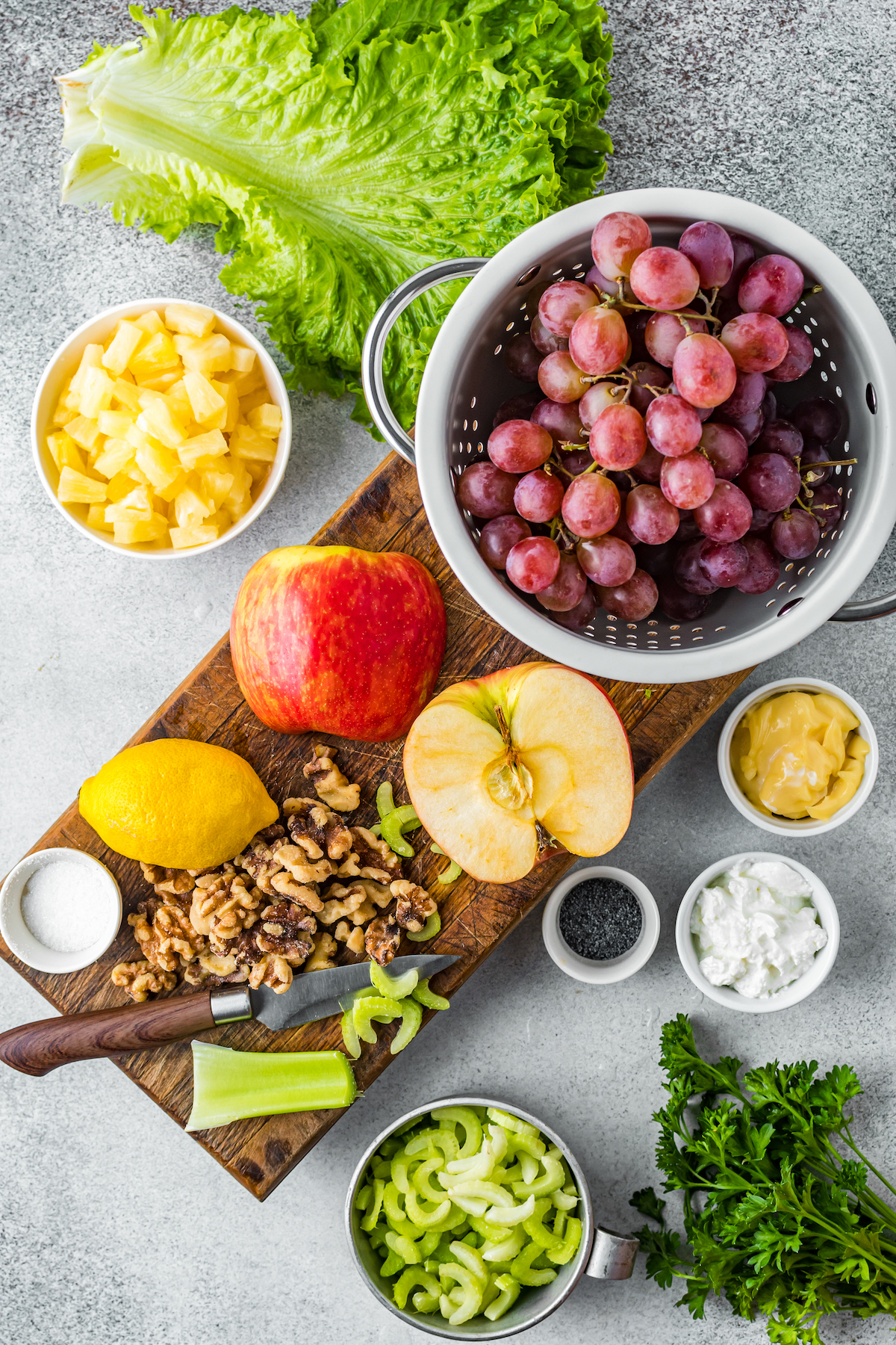 Left to right, from top: pineapple chunks, grapes, mayonnaise, greek yogurt, poppy seeds, mint, apple, chopped nuts, celery, lemon.