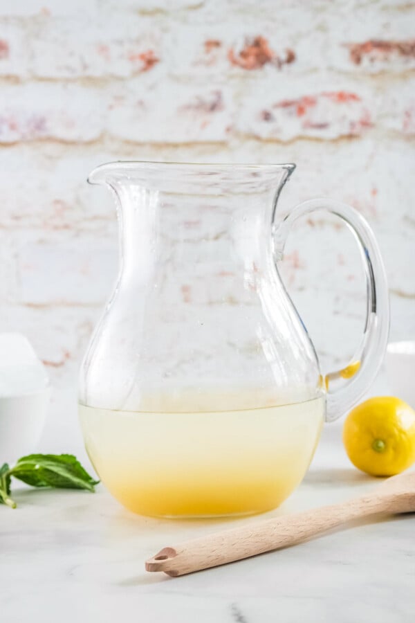 Lemonade concentrate and water in a glass pitcher.
